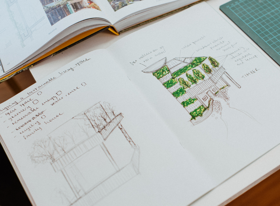 An open sketch book with drawing of buildings with green ink.