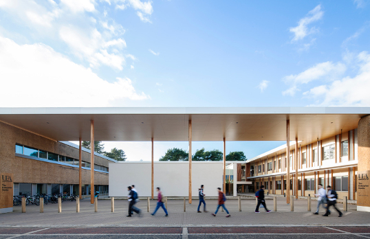 Open concept flat roof building with people walking past in the foreground