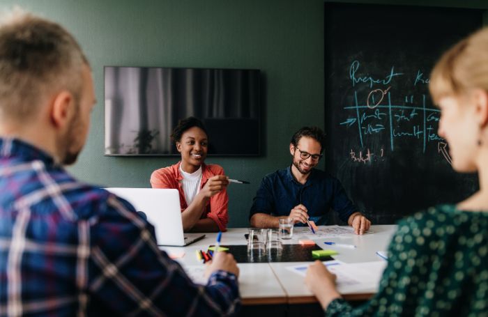 Group of people sitting around a desk and dicussing a project LARGEjpg
