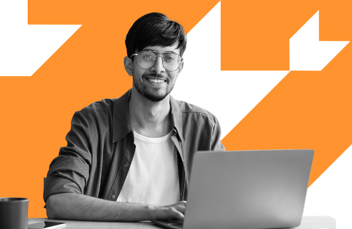 Man smiling to the camera while working on a laptop LARGEpng