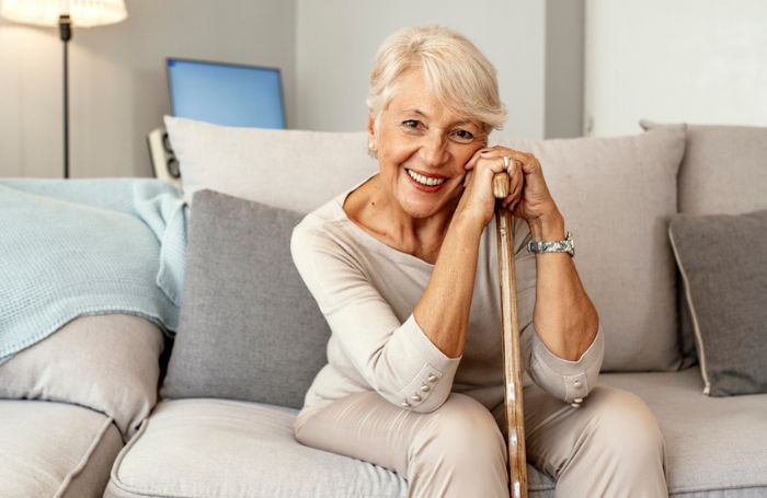 Older woman pictured in a living room at home with her walking stick LARGEjpg