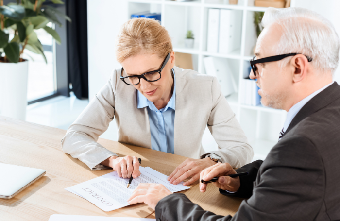 Two white people sitting looking at a contract 700x455png