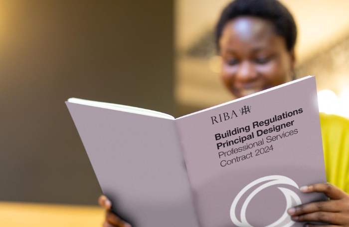 A woman reading a book entitled RIBA Building Regulations Principle Designer