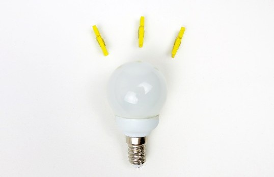 Three yellow pegs fan out above a lightbulb