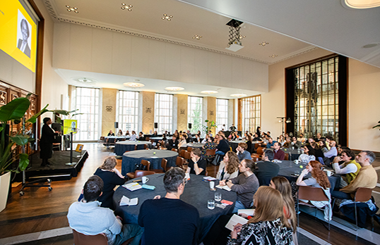 A hall full of round table discussion groups in conference.