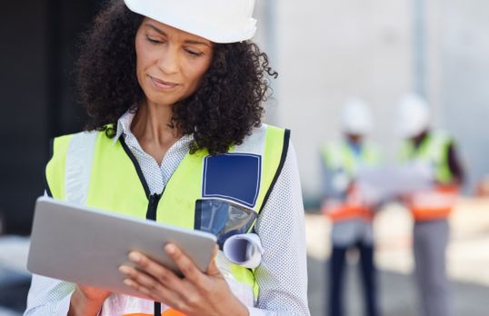 A female architect on a building site wearing a hard hat and hi viz