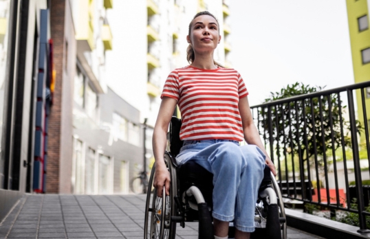 A female wheelchair user on a ramp outside a building