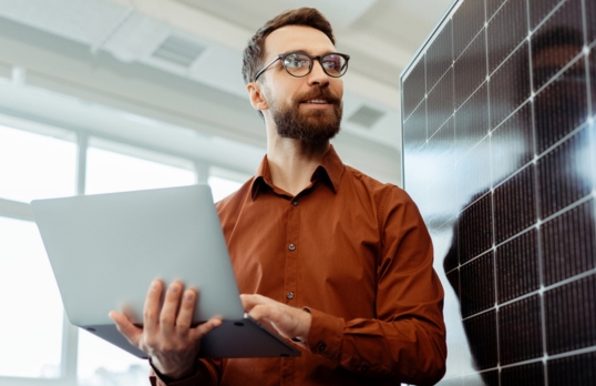 Architect with beard holding a laptop and looking into the distance