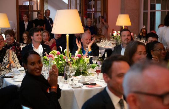 Audience clapping at a Stirling Prize event. They are seated at tables and dressed formally.