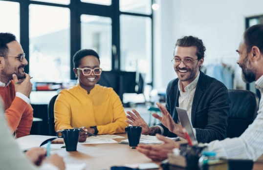 A diverse group of people in an office chatting around a table