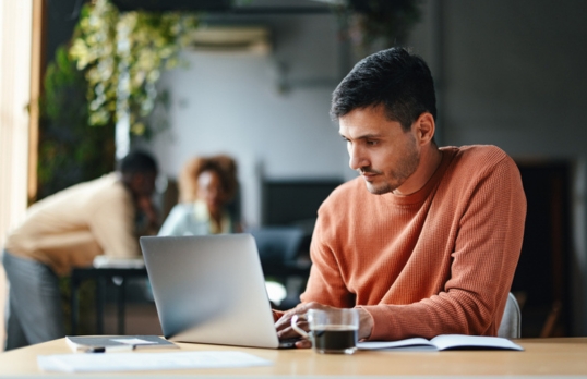 Man in an office focusing hard on a laptop 