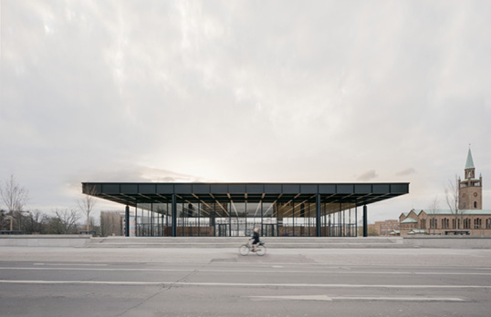 Street level view of Neue Nationalgalerie, a low profile glass and dark metal roofed structure