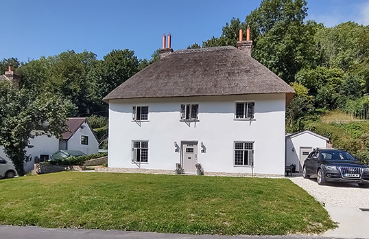 Restored Cob House, a white rectangular house with a thatched roof