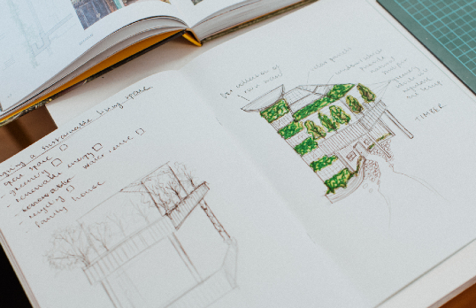 An open sketch book with drawing of buildings with green ink.
