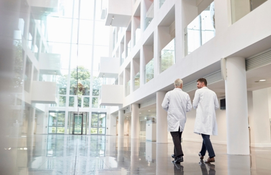 Two doctors walking through a modern hospital with shiny floors and white walls