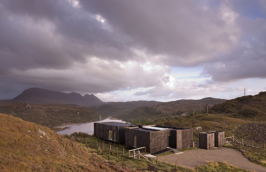 A modern low profile brown building between hills