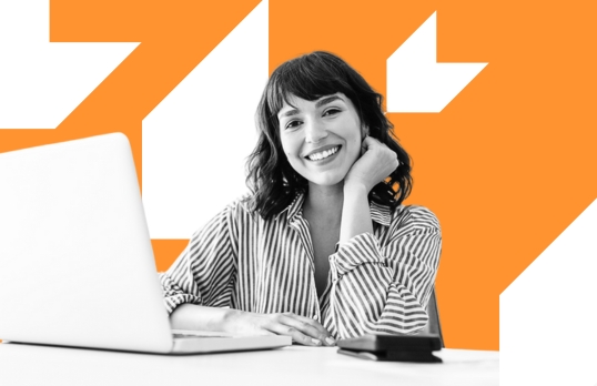 Woman sitting behind a desk smiling on an orange background