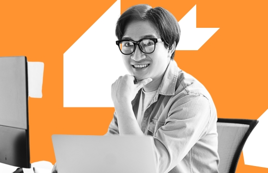 Woman smiling working on computer with orange background