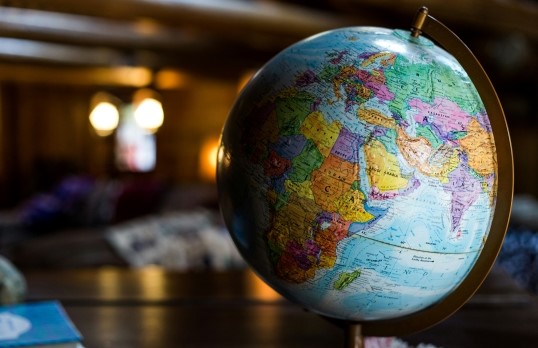 A globe of the world set against a blurred office background