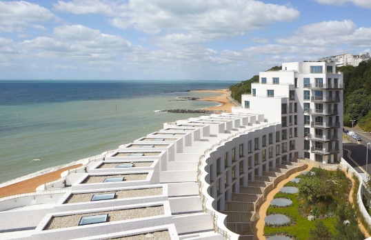 Curved row of white rooftops on beachside location with blue sky