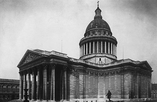 Black and white photograph of the Pantheon in Paris, neoclassical columned ground floor and upper tower that is round with a dome roof