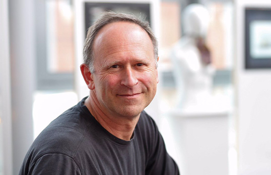 Man wearing a grey tee and smiling at camera