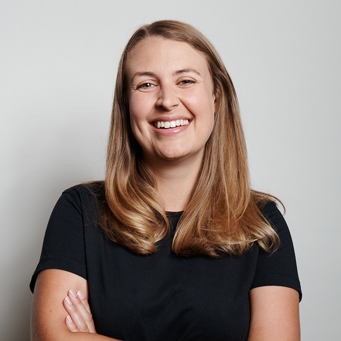 Rachael Owens - RIBA Stirling Prize 2023 jury member with shoulder length light brown hair and a black tshirt, smiling and crossing her arms