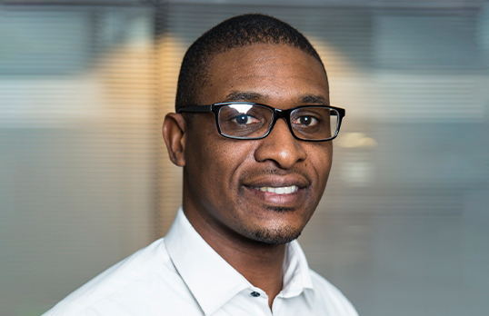 Colin Glen wearing glasses and a white button-up shirt smiling to camera