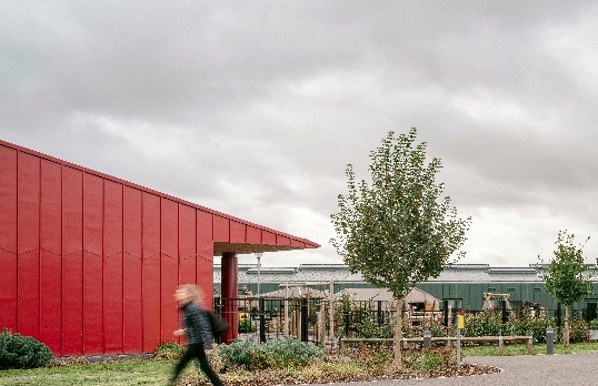 Bold red metal clad gable with large overhang cover set in hillside location