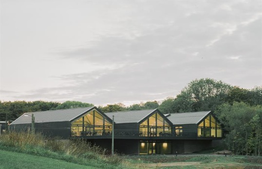 Trio of simple barn-like buildings clad in metal set into the rural surroundings
