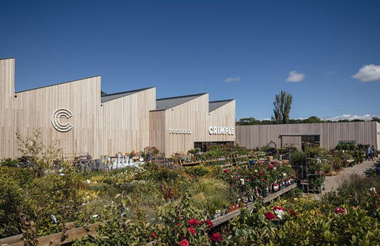 Saw tooth ridged building in pale wooden timber cladding with extensive kitchen gardens