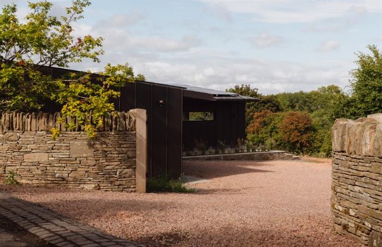 Single storey black clad dwelling set amongst greenery