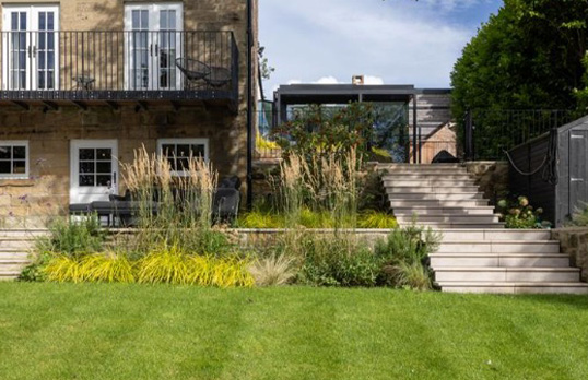 Small modern black box building set back from manicured lawns and existing buildings