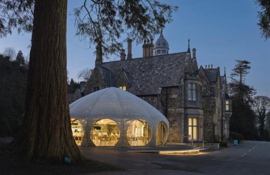 Intricately laser cut metal cladding onion shaped building extension to a traditional stone building.