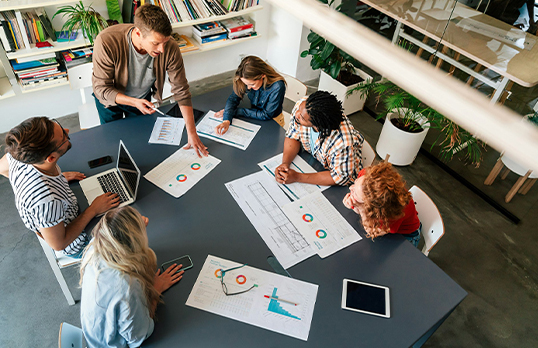 Group of people at a table discussing graphs and data on paper