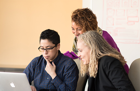 Three women looking at a laptop screen