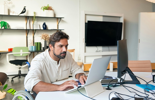 Man in a wheelchair at a desk with computers
