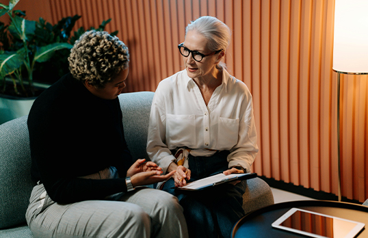 Older and younger woman on a sofa looking at a piece of paper