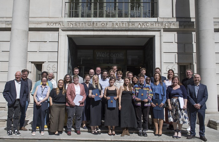 Students standing and smiling outside the entrance to 66 Portland Place