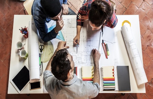 Three architects discussing a floorplan