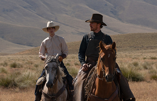 Two cowboys on horseback with hills in the background, from the film The Power of the Dog
