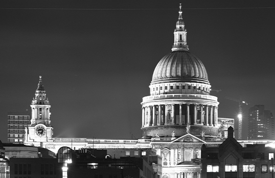 Black and white nighttime photograph of a lit up dome of St Paul's Cathedral in London