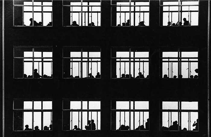 Black and white photograph of classroom windows with silhouettes of students 