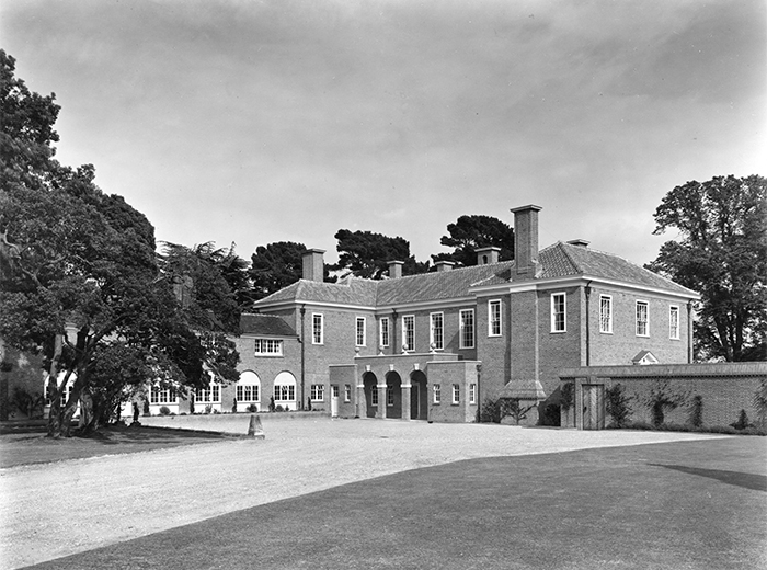 Black and white photograph of Great Swifts, Kent - a large brick estate home with hip roof, small windows and a large drive leading to the house