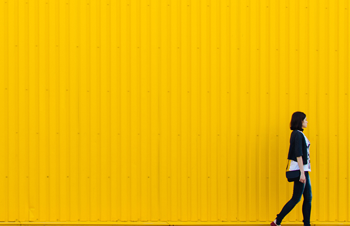 woman walking across a yellow tiled background 