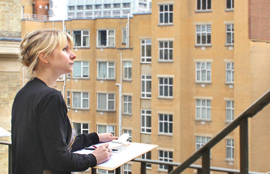 A woman with a sketchpad looks at a building in a drawing workshop at the RIBA, 66 Portland Place, London