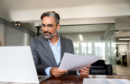 Person looking at laptop and insurance documents 