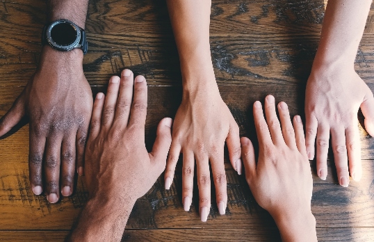 Different people's hands placed on a table