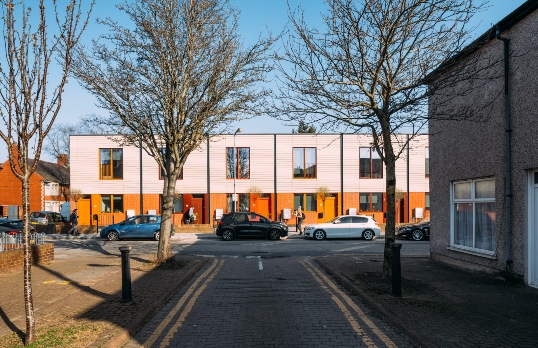 Wales terraced housing project with cars parked in front and bare trees in the foreground
