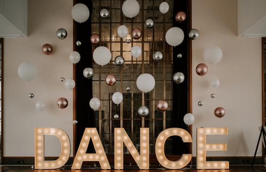 Balloon decorations and a light up sign that spells 'Dance' in front of a Art Deco window